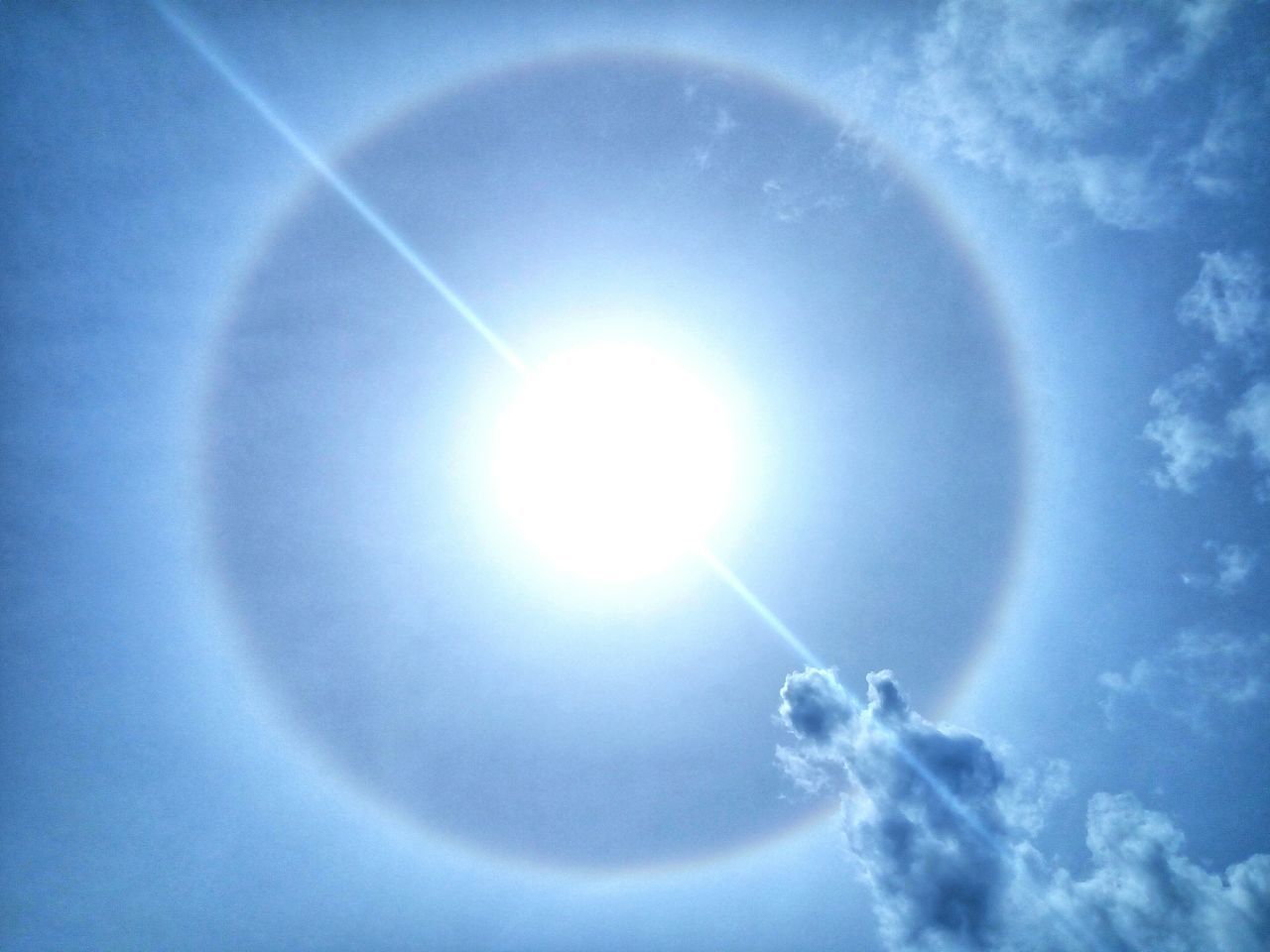 LOW ANGLE VIEW OF SUN SHINING OVER VAPOR TRAIL IN SKY