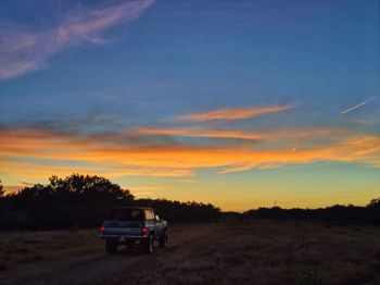 Car on field against sky during sunset