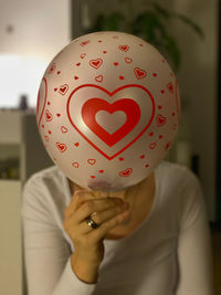 Close-up portrait of woman holding heart shape