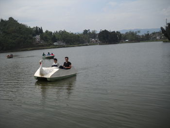 People in boat on lake against sky