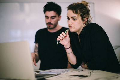 Business people discussing over laptop at desk in creative office