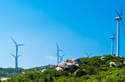 Low angle view of electricity pylon against clear blue sky