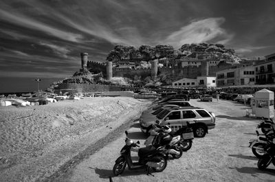 Vehicles parked at beach against castle