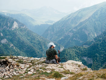 Man sitting on mountain looking at mountains