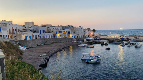 High angle view of sea and buildings against sky during sunset