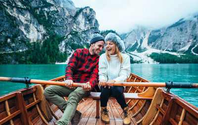 Young couple sitting on boat against mountains