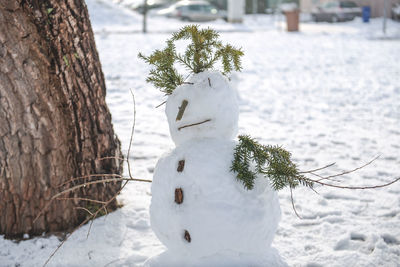 Snowman by tree on field