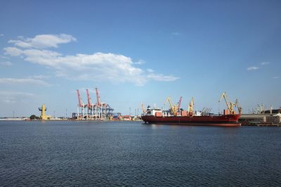 Cranes at harbor against sky