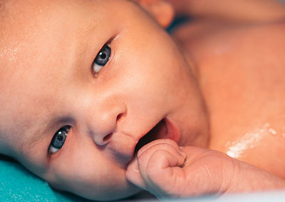 Close-up of toddler with gray eyes lying on bed