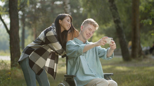 Man on wheelchair taking selfie with girlfriend at park