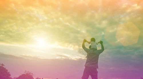 Rear view of woman standing against sky during sunset