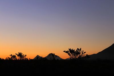 Scenic view of silhouette mountains against orange sky