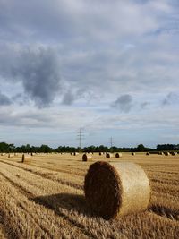 Hay bales on field against sky