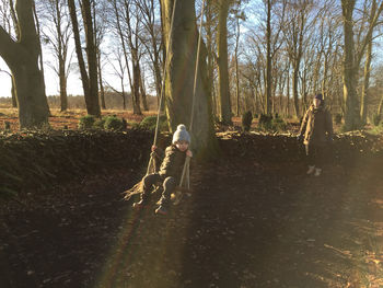 Father and son walking on bare tree in forest