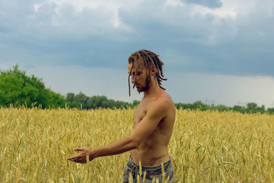 Shirtless young man gesturing while standing at farm