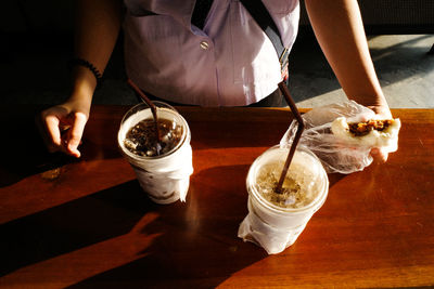 Midsection of woman pouring drink in glass on table