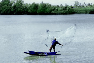 Man in boat on sea against trees