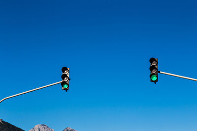 Low angle view of road signal against clear blue sky