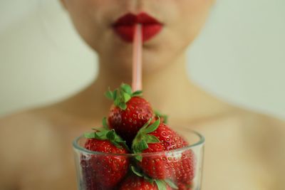 Cropped image of naked woman with strawberries in glass