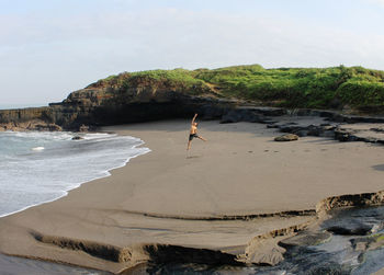 Full length of man on rocks at beach against sky