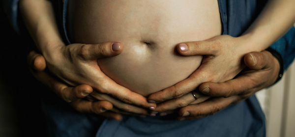 Cropped hands of man touching pregnant girlfriend abdomen
