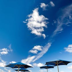 Low angle view of parasols against blue sky