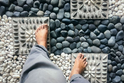 Low section of man standing on pebbles