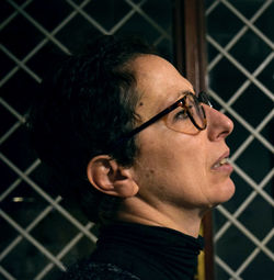 Close-up of woman looking away against fence