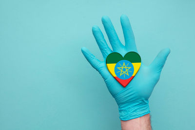 Close-up of hand holding heart shape against blue background