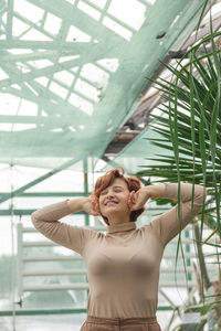 A beautiful plus size girl enjoying standing among the green plants of the greenhouse. 