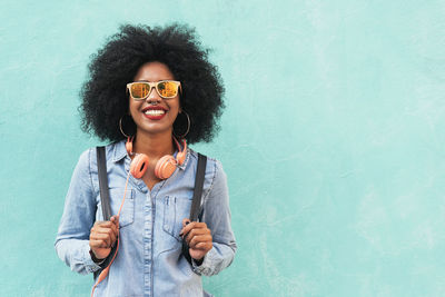 Portrait of smiling young woman standing against wall