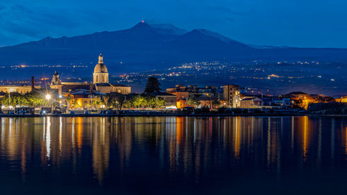 The city of riposto illuminated in the sky of the blue hour after sunset