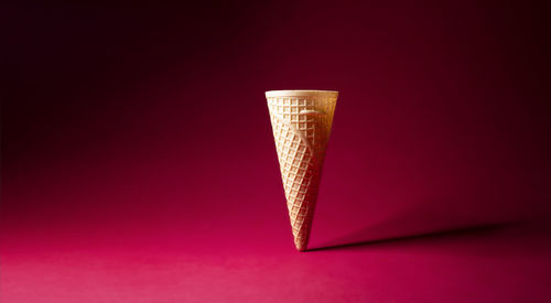 One empty waffle cone on red background.