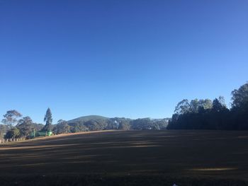 Road by landscape against clear blue sky