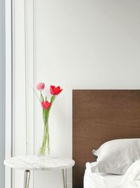 Rose flower vase on table against wall at home