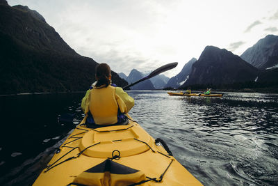 Rear view of woman on lake against mountain range