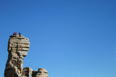 Low angle view of man standing on rock against clear blue sky in tucson arizona usa