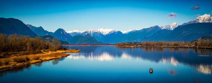 Scenic view of lake and mountains against blue sky