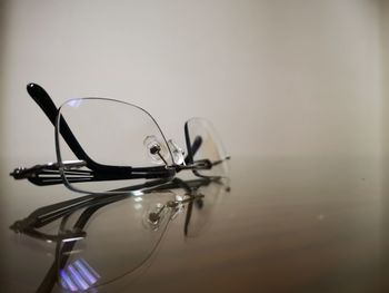 Close-up of eyeglasses on table against wall