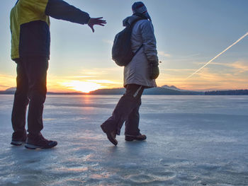 Cute couple in bay of frozen sea. they hold together at the frozen pond near sandy beach