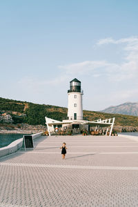 Rear view of woman walking on beach against sky