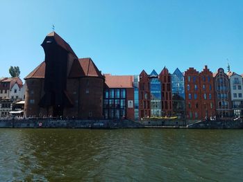 Buildings at waterfront against blue sky