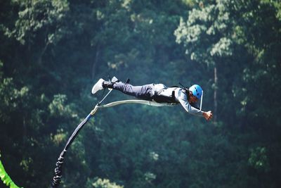 Low angle view of man with rope against trees