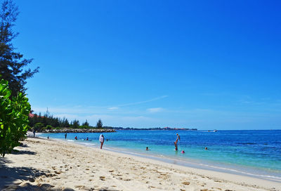 People at beach against blue sky