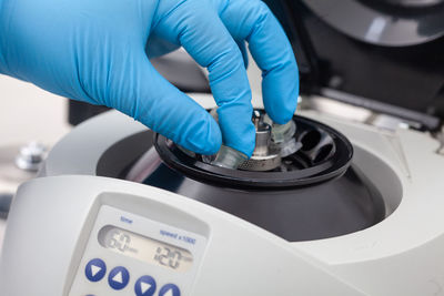 Closeup of a scientist hand placing a tube into an small table centrifuge.