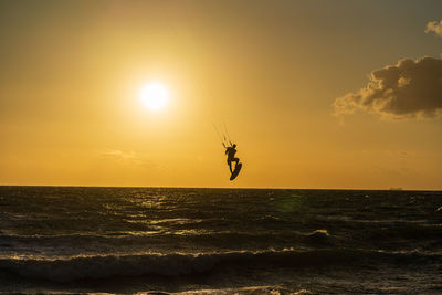 Kite surfer jumping against the sunset