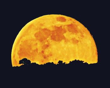 Close-up of yellow moon against sky at night