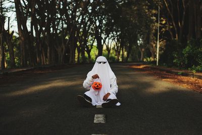 Man sitting on road amidst trees in city