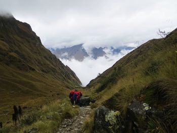 Rear view of people on mountain against sky