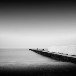 Pier at beach against sky during foggy weather